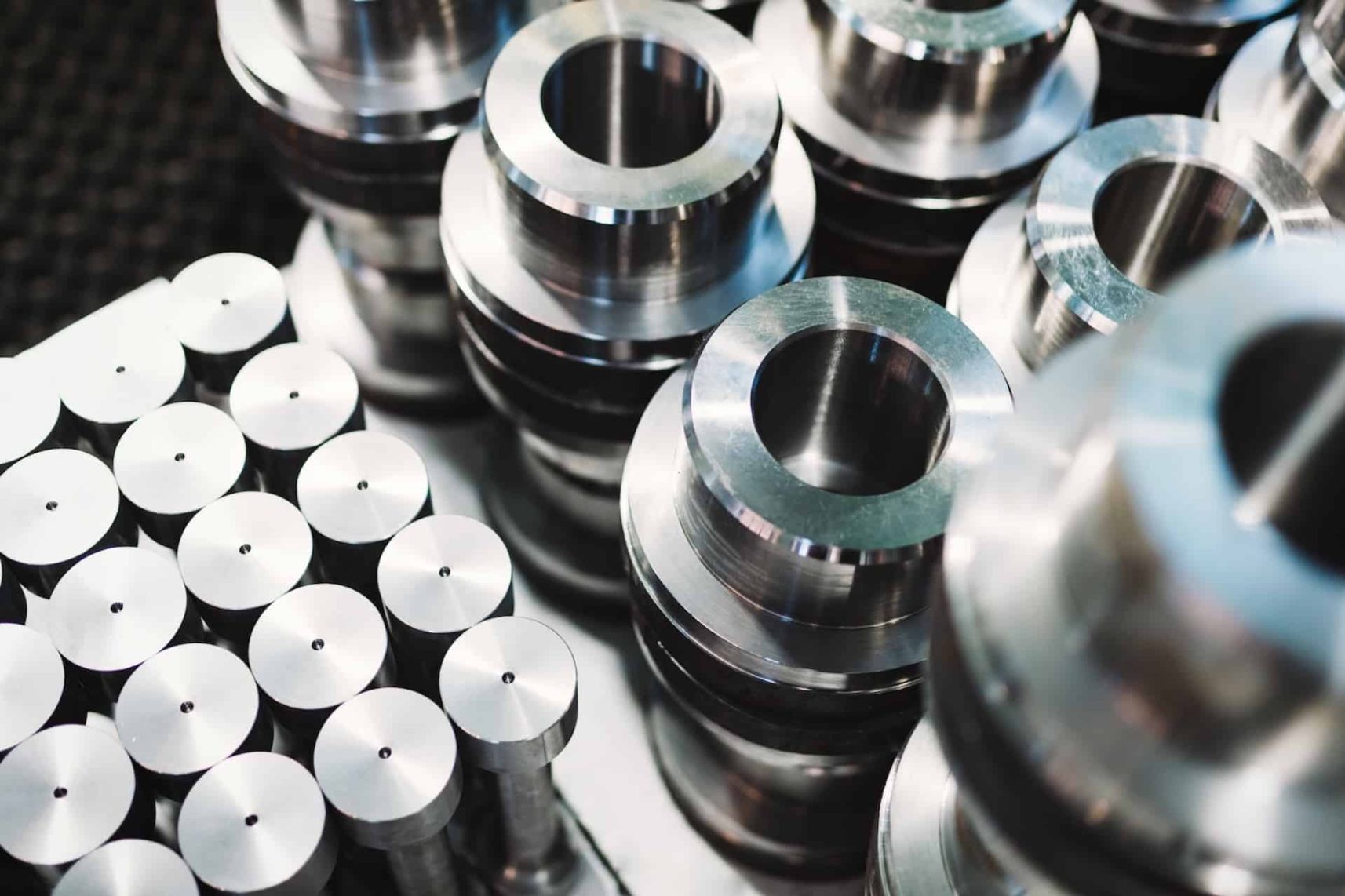 Close-up of CNC-machined steel parts: stepped bushings and turned cylindrical pins from a German metal manufacturer